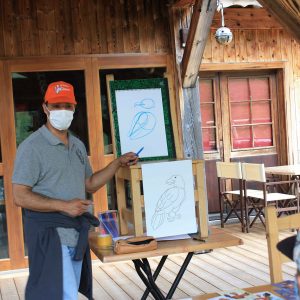 Dessinateur vincent en train de faire une démonstration sur la terrasse du restaurant devant son public.