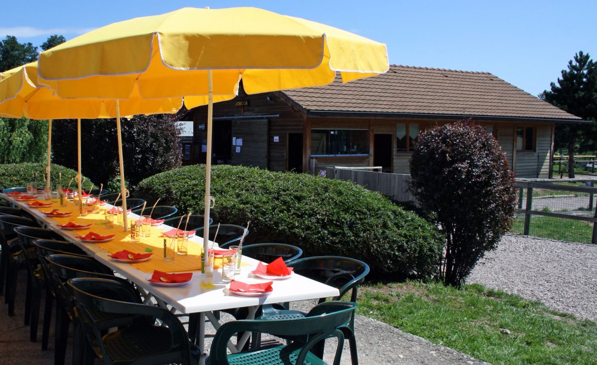 Photo de la mise en place d'une table d'anniversaire prête pour recevoir ses convives. Les couleurs sont rouges et jaunes.