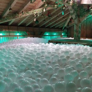 Piscine à balles sans personnes à l'intérieur du restaurant de Morzine avec de la lumière verte et un arbre.